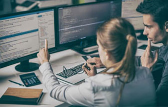 A woman sitting at her desk with two computers.